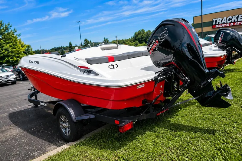 Slide: The Image of 2026 Tahoe T18 boat with red and white design, parked on grass near dealership. - 1
