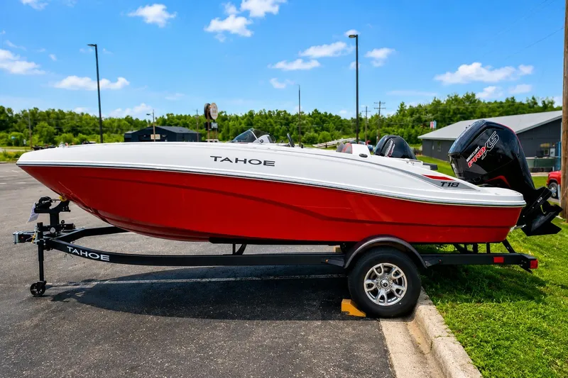 The Image of 2026 Tahoe T18 boat in red and white on a trailer, parked outdoors. - 0