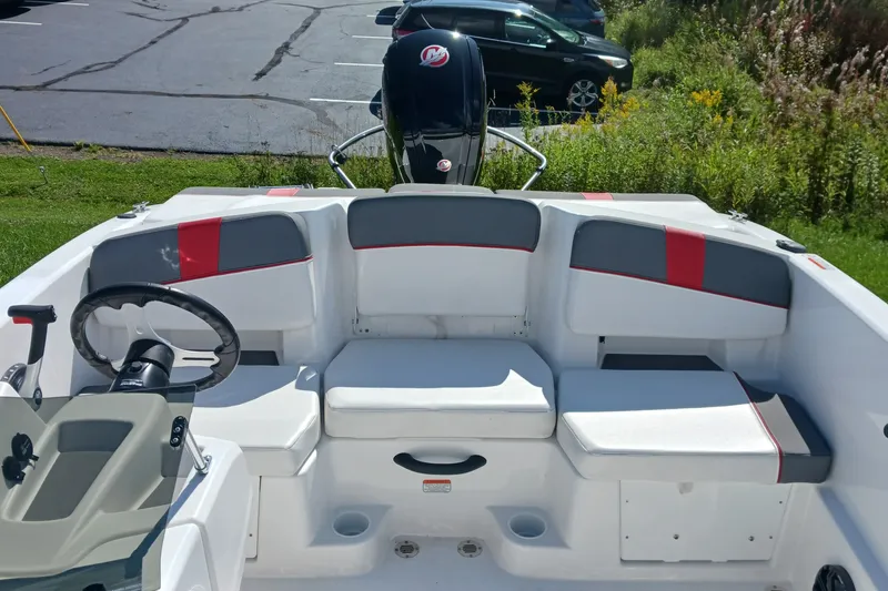 Slide: The Image of 2026 Tahoe T18 boat interior with seating and steering wheel, parked outdoors. - 7