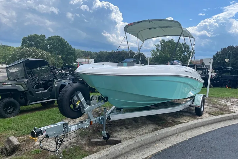 The Image of 2026 Tahoe T18 boat on trailer with canopy, parked outdoors under cloudy sky. - 0