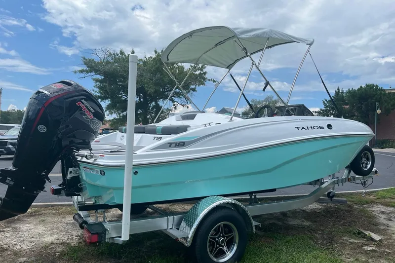 Slide: The Image of 2026 Tahoe T18 boat on trailer with canopy, parked outdoors under cloudy sky. - 2