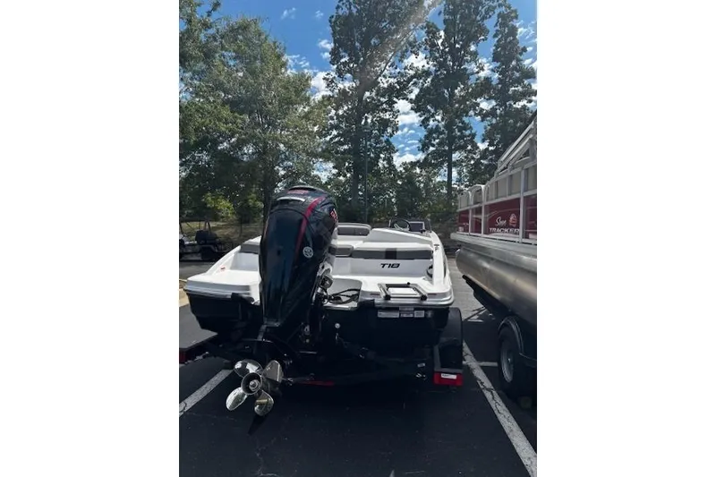 Slide: The Image of 2026 Tahoe T18 boat with outboard motor in parking lot, surrounded by trees. - 4
