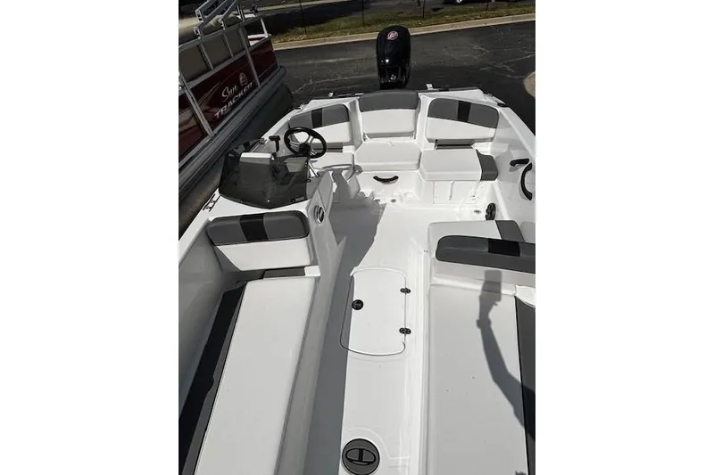 Slide: The Image of 2026 Tahoe T18 boat interior with seating and steering wheel, docked beside another vessel. - 5