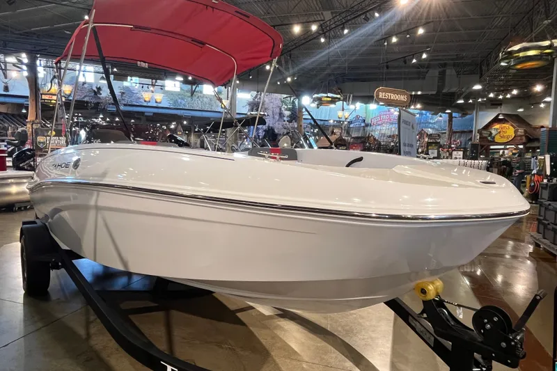 Slide: The Image of 2026 Tahoe T18 boat with red canopy displayed indoors on a trailer. - 2
