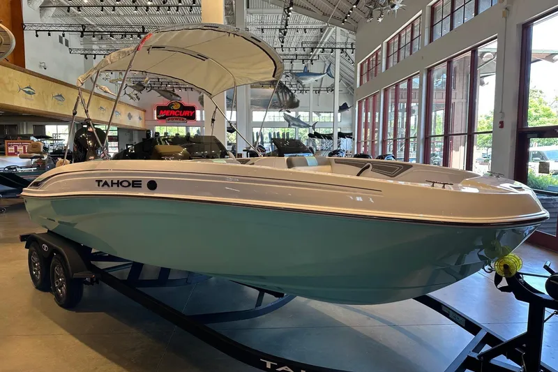 Slide: The Image of 2026 Tahoe T21 boat displayed indoors with canopy and trailer. - 1