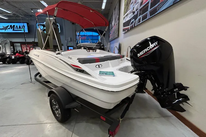 Slide: The Image of 2026 Tahoe T18 boat with Mercury engine, displayed indoors with red canopy. - 1