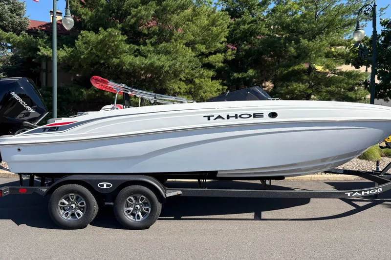 Slide: The Image of 2026 Tahoe T21 boat on trailer, parked outdoors with trees in background. - 5