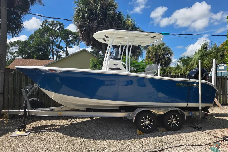 The Image of 2018 Sea Pro 219 Center Console boat on trailer, parked outdoors under blue sky. - 1