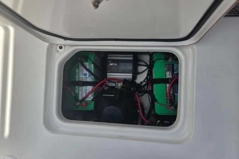 Slide: The Image of 2018 Sea Pro 219 Center Console battery compartment with wiring and green batteries. - 19