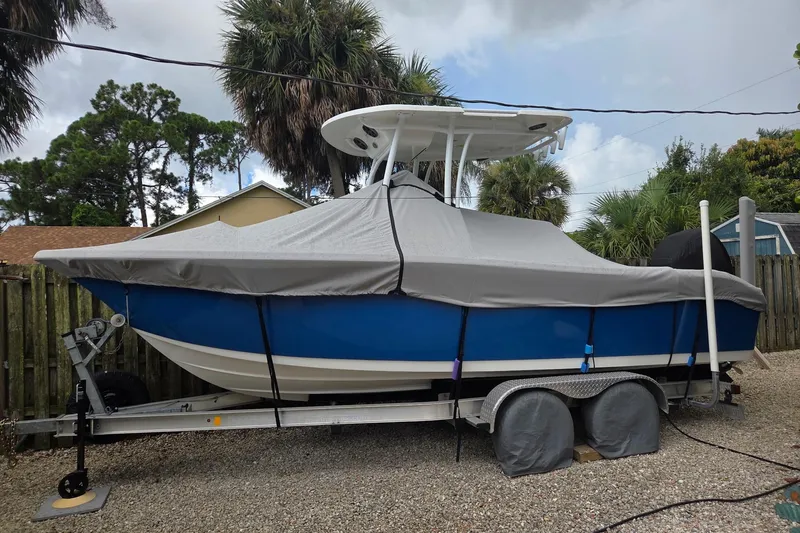 Slide: The Image of 2018 Sea Pro 219 Center Console boat covered on a trailer, surrounded by trees. - 4