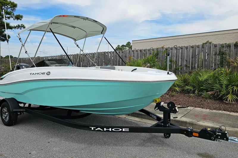 Slide: The Image of 2026 Tahoe T18 boat with canopy on trailer, parked outdoors. - 4