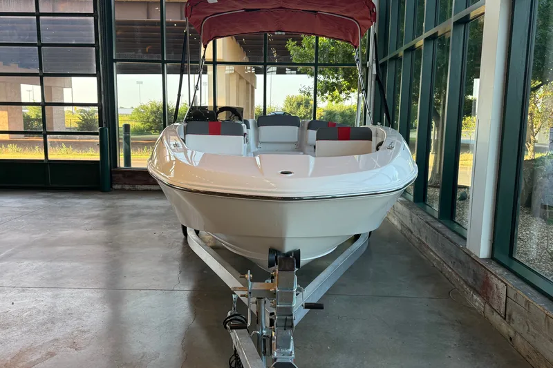 Slide: The Image of 2026 Tahoe T18 boat with red canopy, displayed indoors on a trailer. - 2