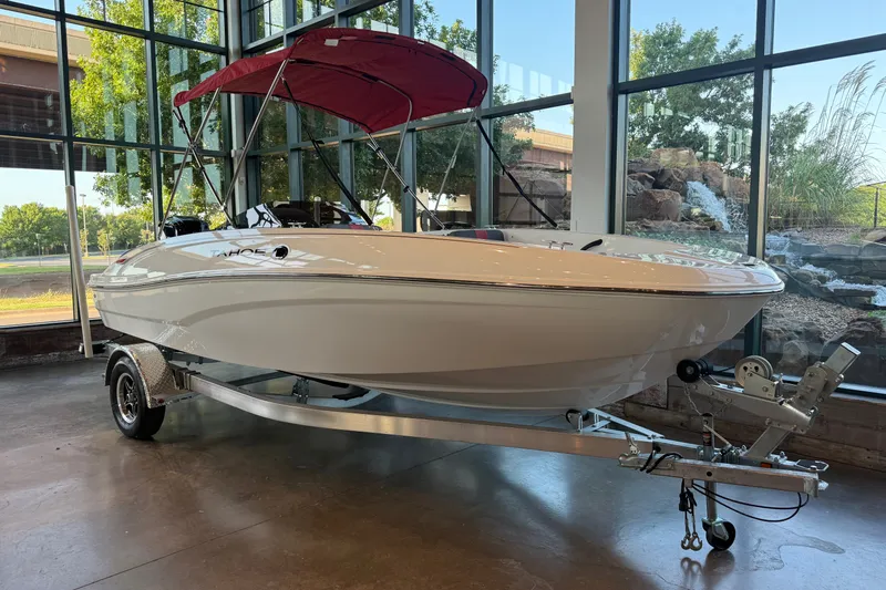 Slide: The Image of 2026 Tahoe T18 boat with red canopy on display in a showroom. - 1