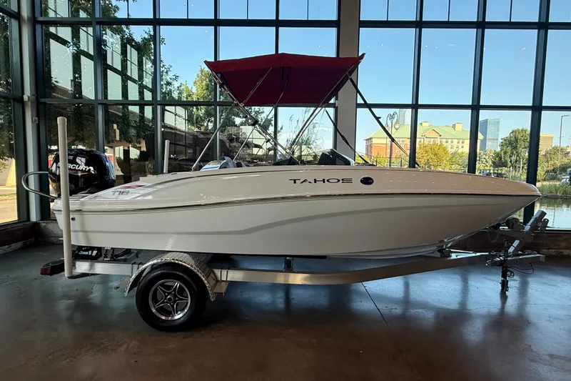 The Image of 2026 Tahoe T18 boat with red canopy on display indoors, featuring sleek design and trailer. - 0
