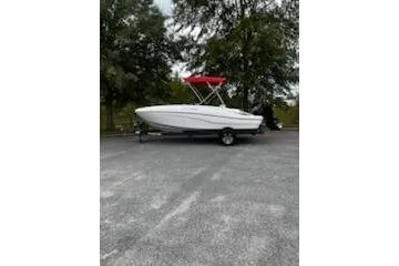 The Image of 2026 Tahoe T18 boat with red canopy on a trailer, parked outdoors. - 1