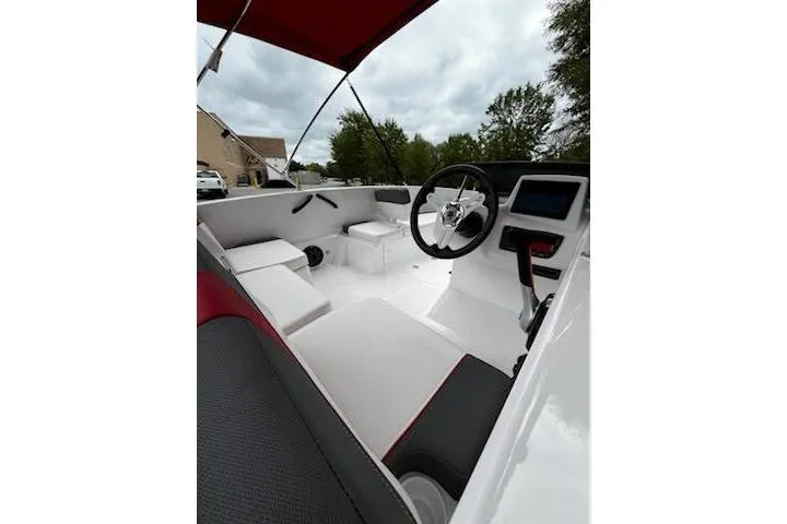 Slide: The Image of 2026 Tahoe T18 boat interior with steering wheel, seating, and canopy under cloudy sky. - 7