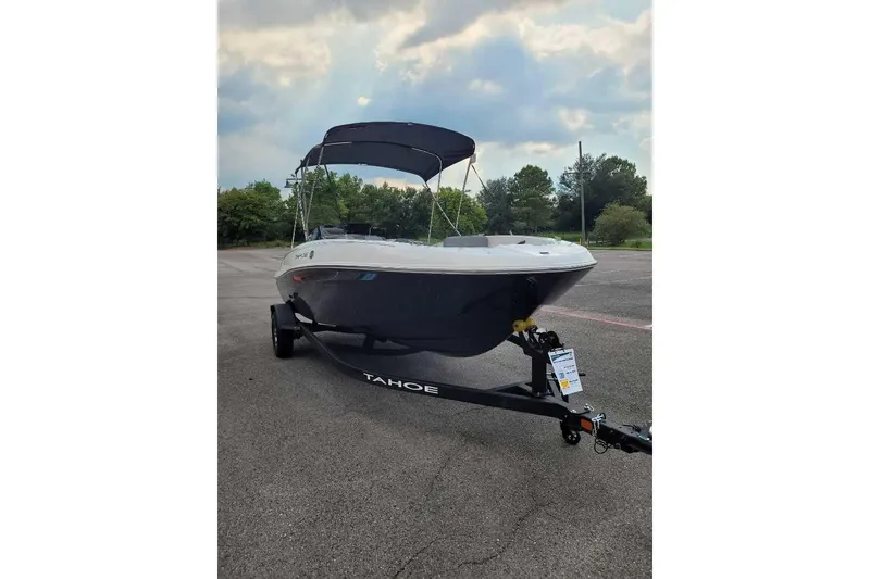 Slide: The Image of 2026 Tahoe T18 boat on trailer, parked outdoors under cloudy sky. - 2