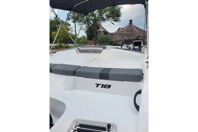 Slide: The Image of 2026 Tahoe T18 boat with cushioned seating and canopy, parked outdoors. - 4