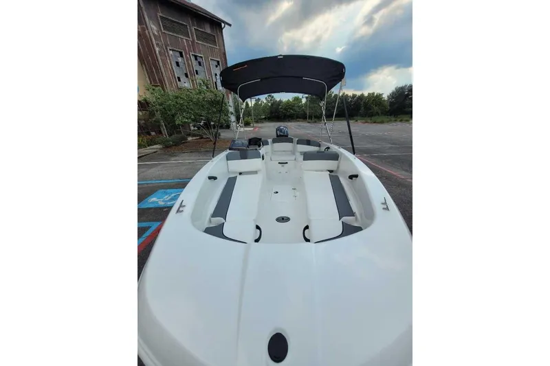 Slide: The Image of 2026 Tahoe T18 boat with canopy, parked near rustic building under cloudy sky. - 5