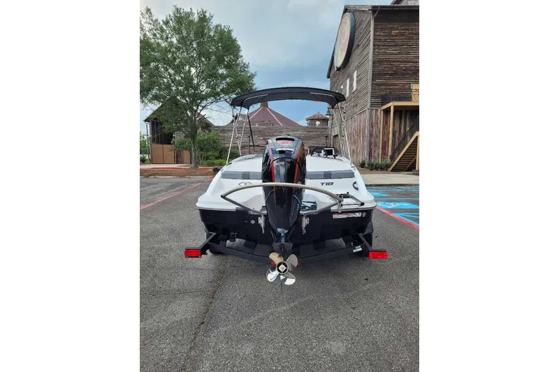 Slide: The Image of 2026 Tahoe T18 boat rear view in a parking lot, showcasing outboard motor and trailer. - 6