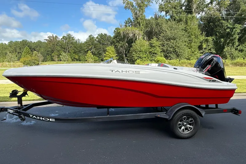 The Image of 2026 Tahoe T18 boat in red and white on a trailer, parked outdoors. - 0