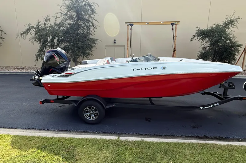 Slide: The Image of 2026 Tahoe T18 boat with red hull on trailer, parked outdoors. - 1