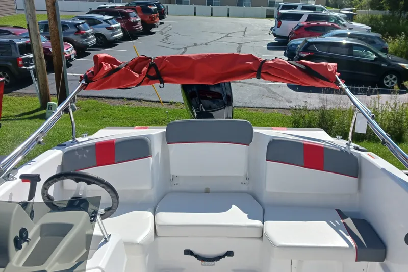 Slide: The Image of 2026 Tahoe T16 boat interior with red canopy, steering wheel, and seating in a parking lot. - 7