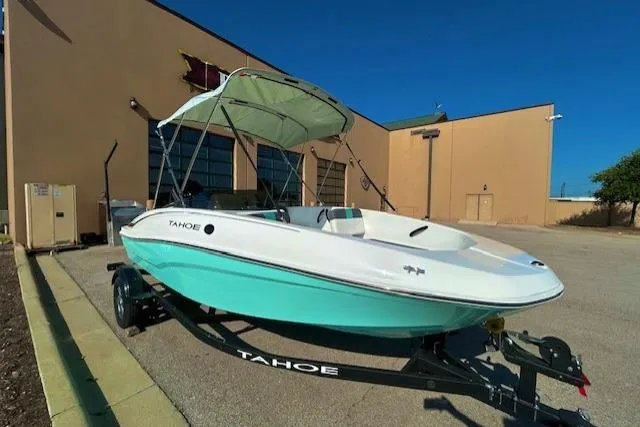 The Image of 2026 Tahoe T16 boat with canopy on trailer, parked outside a building. - 0