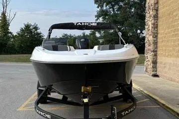 Slide: The Image of 2026 Tahoe T18 boat on trailer, parked outdoors near a building. - 2