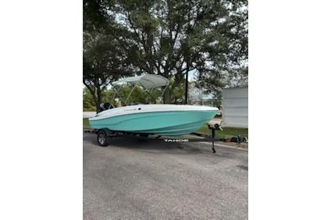 Slide: The Image of 2026 Tahoe T16 boat on trailer, parked outdoors under trees. - 2