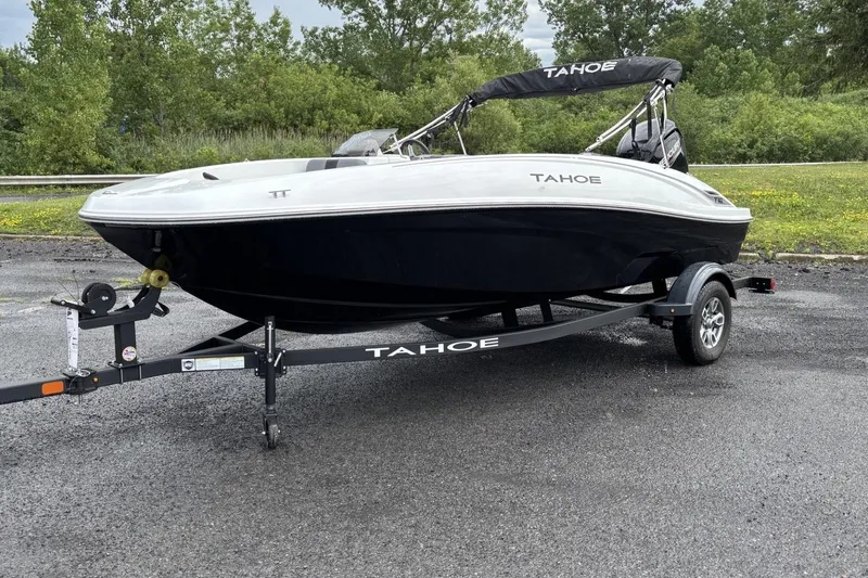 The Image of 2026 Tahoe T16 boat on trailer, parked outdoors with greenery in the background. - 0