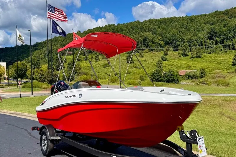 The Image of 2026 Tahoe T18 boat with red canopy on trailer, parked outdoors under blue sky. - 0