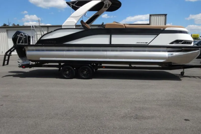 The Image of 2026 Harris Grand Mariner 250 pontoon boat on trailer, parked outdoors under blue sky. - 1