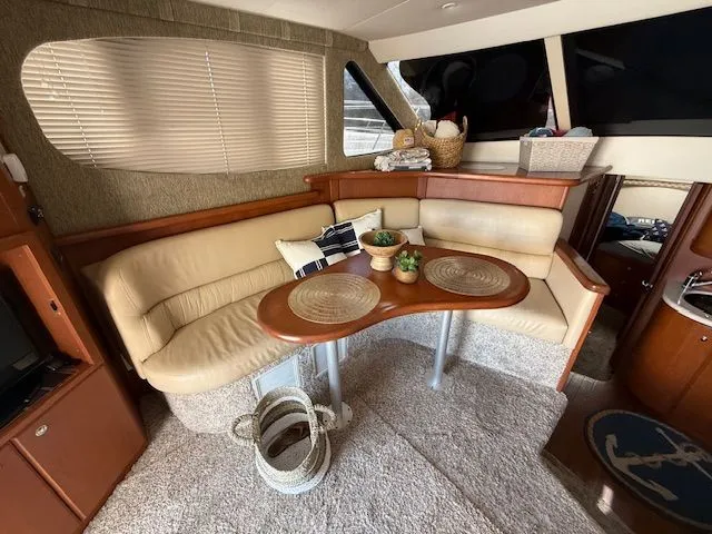 Slide: The Image of Interior of 2004 Silverton 34 Convertible yacht with beige seating and wooden table. - 10
