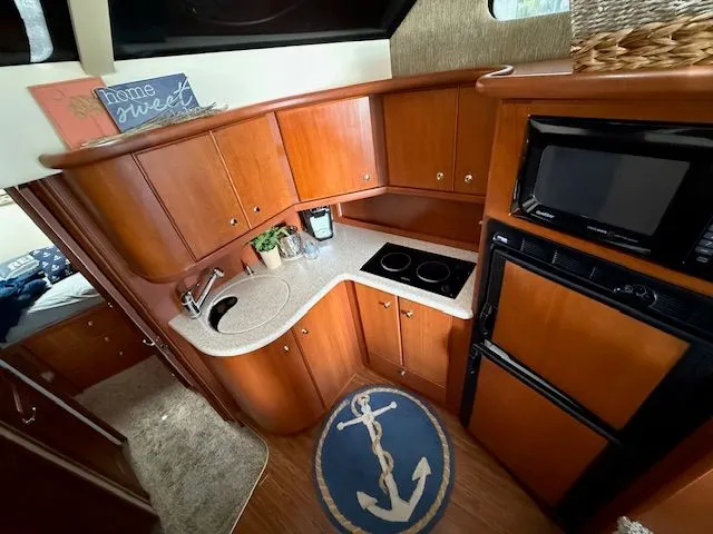 Slide: The Image of 2004 Silverton 34 Convertible yacht kitchen with wood cabinets, stove, microwave, and nautical decor. - 11