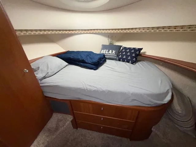 Slide: The Image of 2004 Silverton 34 Convertible cabin with cozy bed, nautical decor, and wooden storage drawers. - 12
