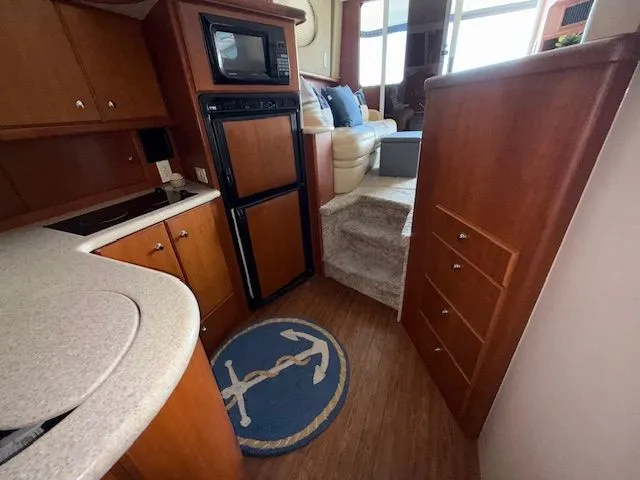 Slide: The Image of 2004 Silverton 34 Convertible yacht interior with kitchen, microwave, fridge, and cozy seating area. - 15