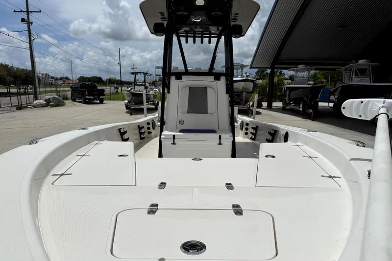 Slide: The Image of 2019 BlackJack 256 boat with spacious deck, parked outdoors under cloudy sky. - 16