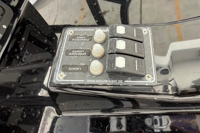 Slide: The Image of Control panel on a 2019 BlackJack 256 boat, featuring light switches and buttons. - 19