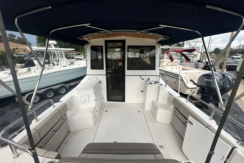 Slide: The Image of 2020 Cutwater C-28 boat interior with seating and canopy, docked alongside other boats. - 13