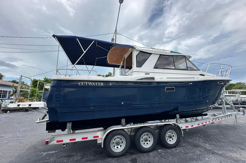 Slide: The Image of 2020 Cutwater C-28 boat on trailer, blue hull, parked outdoors under cloudy sky. - 3