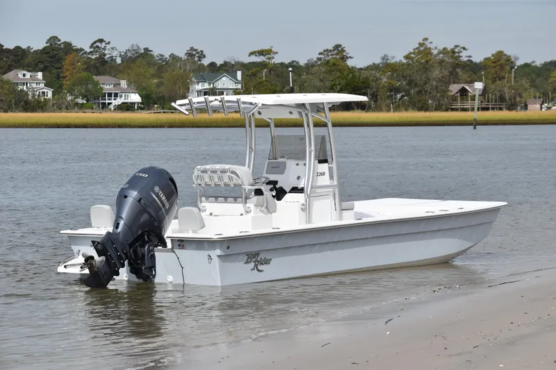 Slide: The Image of 2025 KenCraft 2260 Bay Rider Skiff in shallow water near a sandy shore. - 5