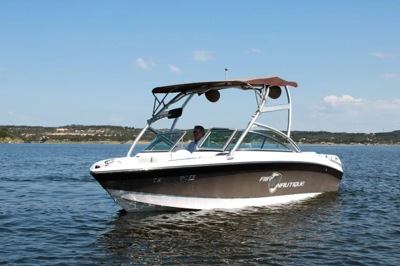 Slide: The Image of 2008 Air Nautique Crossover 236 boat on a calm lake under a clear sky. - 12