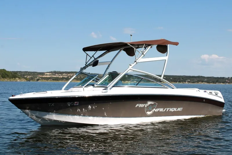 Slide: The Image of 2008 Air Nautique Crossover 236 boat on a calm lake under a clear sky. - 13
