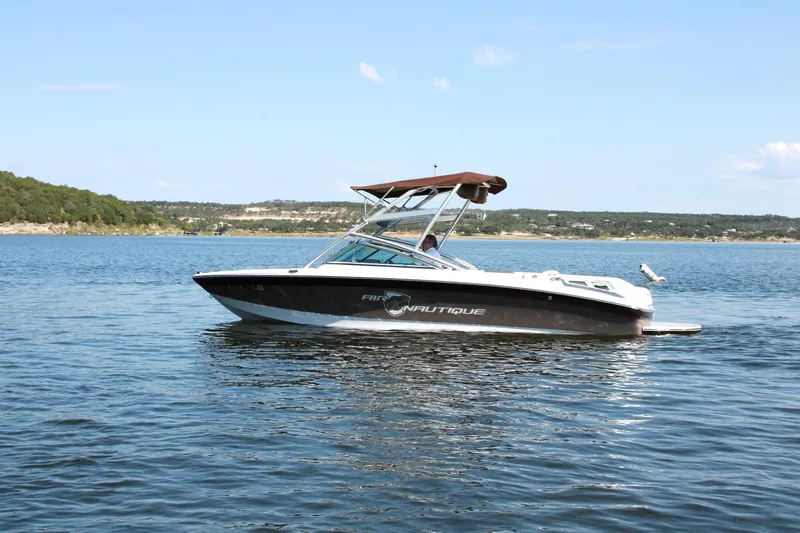 Slide: The Image of 2008 Air Nautique Crossover 236 boat on a serene lake with scenic background. - 16