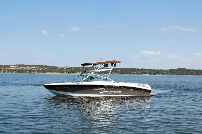 Slide: The Image of 2008 Air Nautique Crossover 236 boat on calm lake under clear sky. - 2