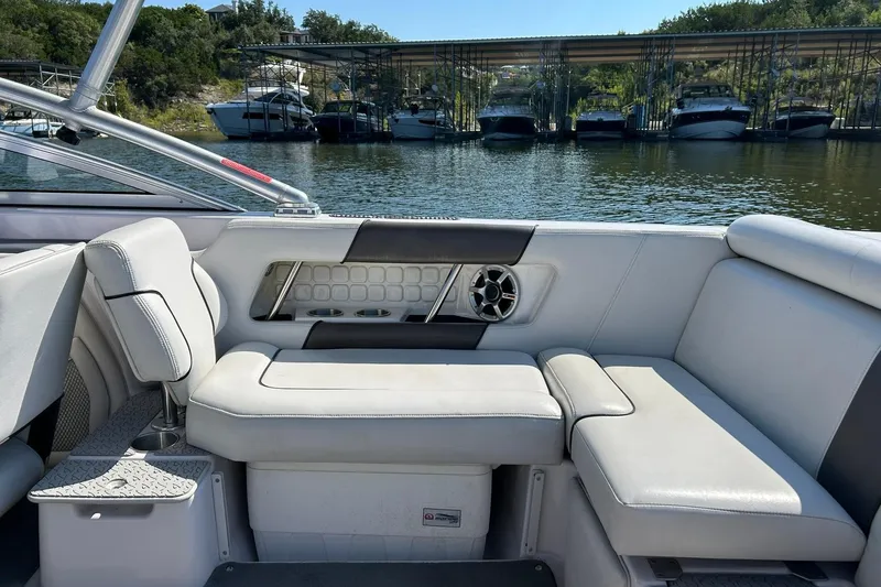 Slide: The Image of 2008 Air Nautique Crossover 236 boat interior with white seating, docked near other boats. - 30