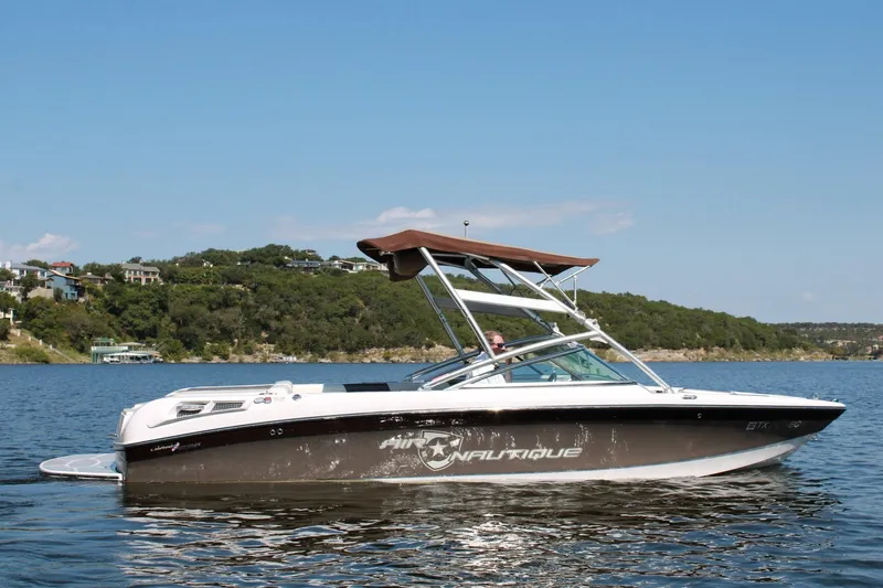 Slide: The Image of 2008 Air Nautique Crossover 236 boat on a scenic lake with lush green hills. - 7