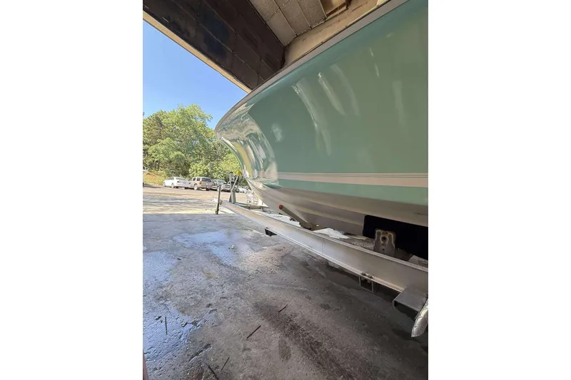 Slide: The Image of 1996 Silverhawk 24 boat on trailer in garage, sunny day, trees in background. - 3