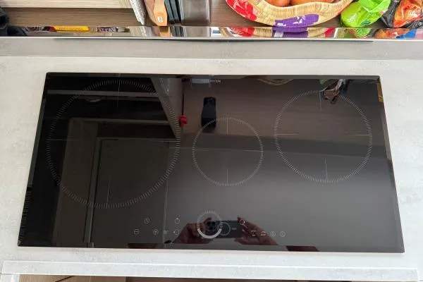 Slide: The Image of Modern induction cooktop with three burners on a sleek kitchen countertop. - 10